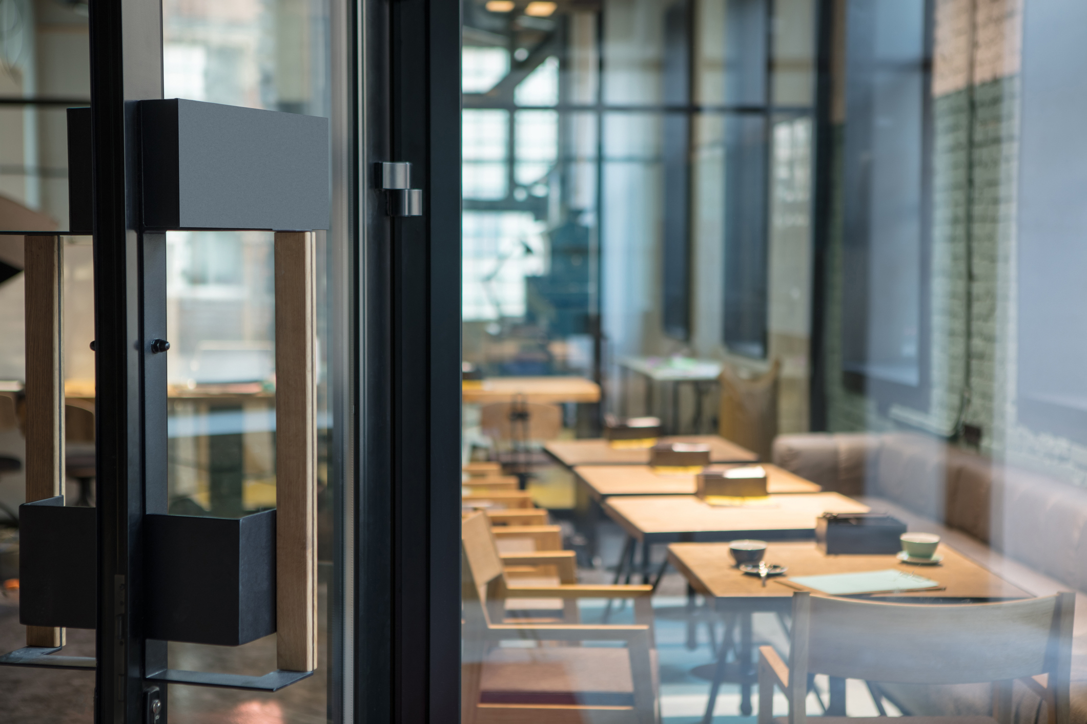 Modern door handle on the wooden glass door in front of the cafe.